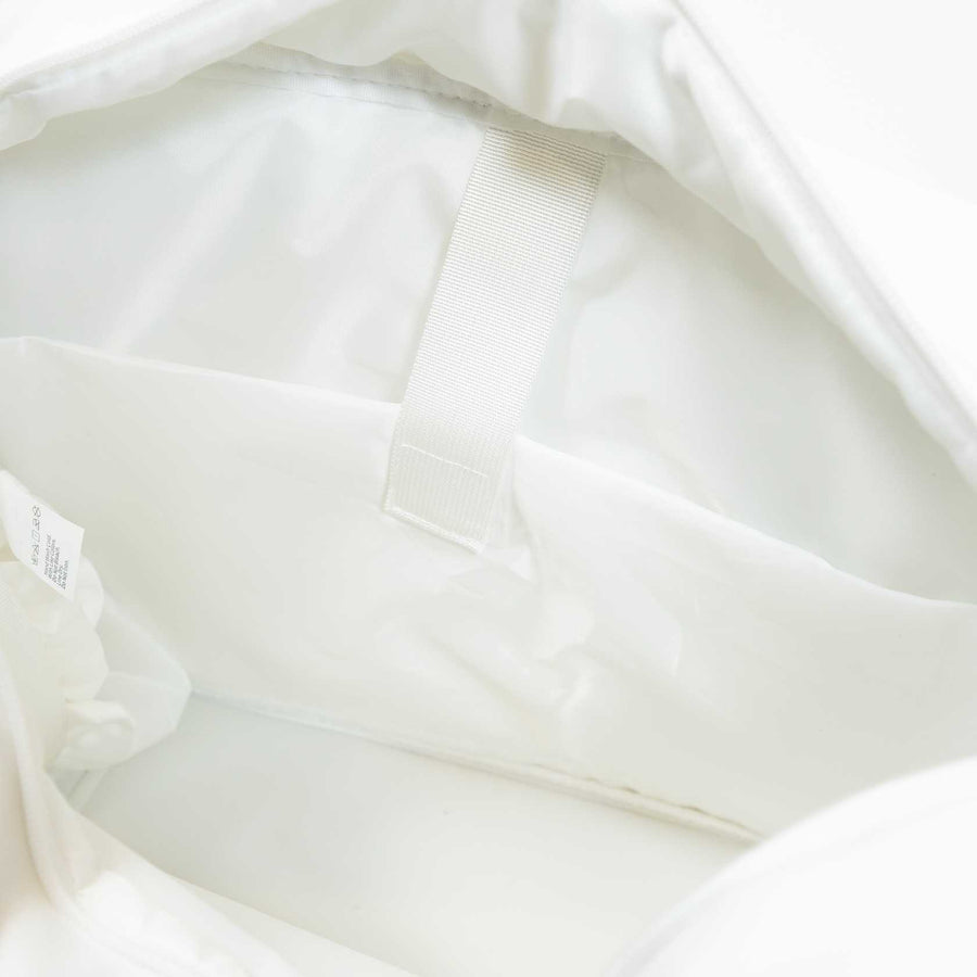 The image shows the inside of the JOOLA Overnighter Puff Bag, a white pickleball bag by JOOLA, featuring a fabric loop and a small inner pocket set against a smooth, light-colored lining and durable construction.