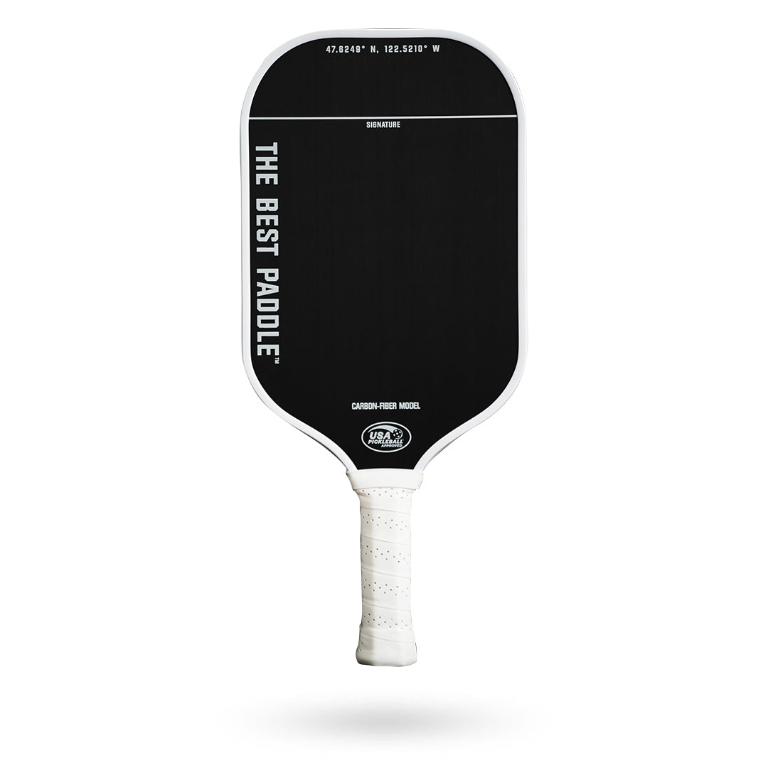 A black and white Pickleballist Carbon Fiber Pickleball paddle labeled "the best paddle" with gps coordinates, displayed against a white background.