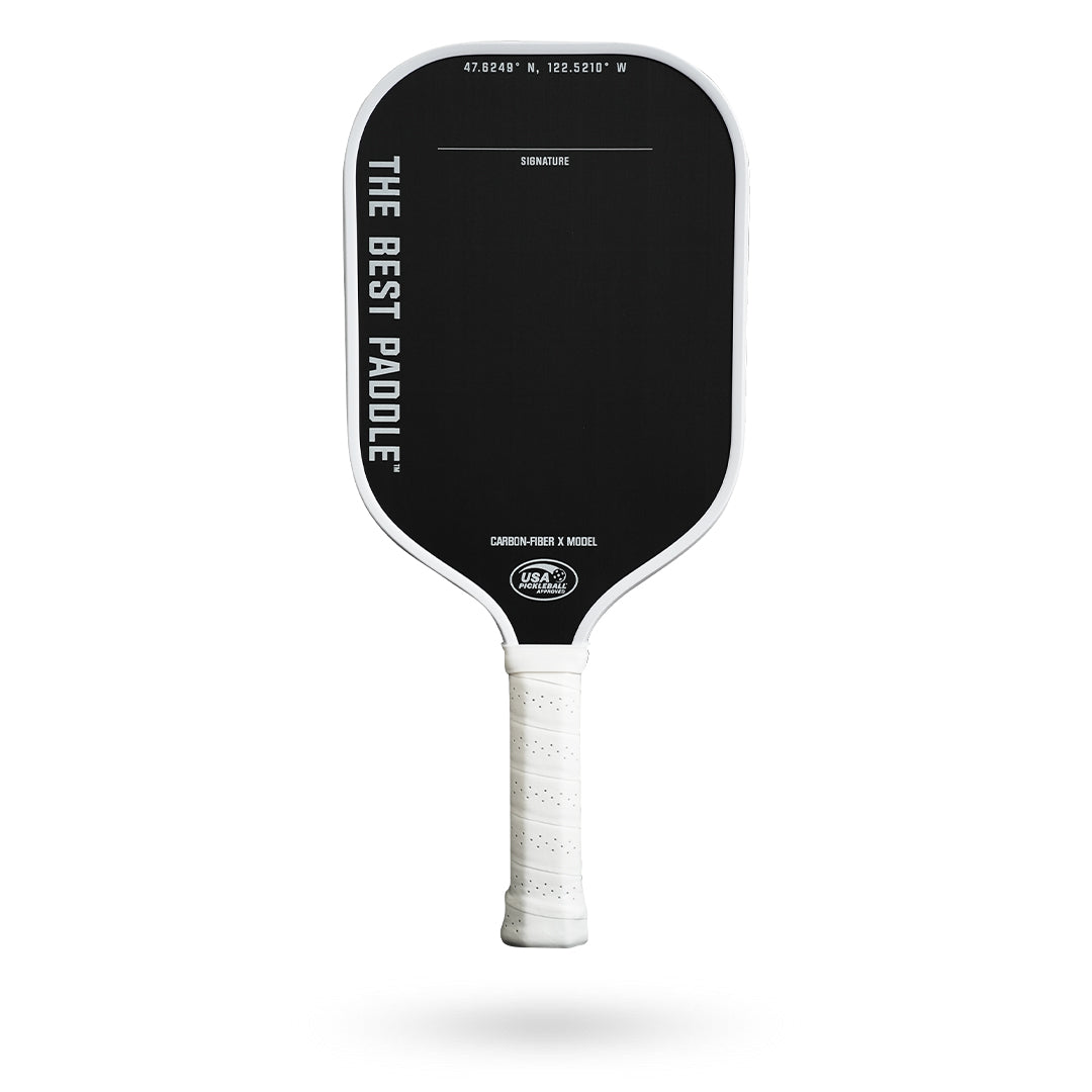 Black and white Pickleballist pickleball paddle labeled "The Best Paddle Carbon Fiber X" with coordinates on top, isolated on a white background.