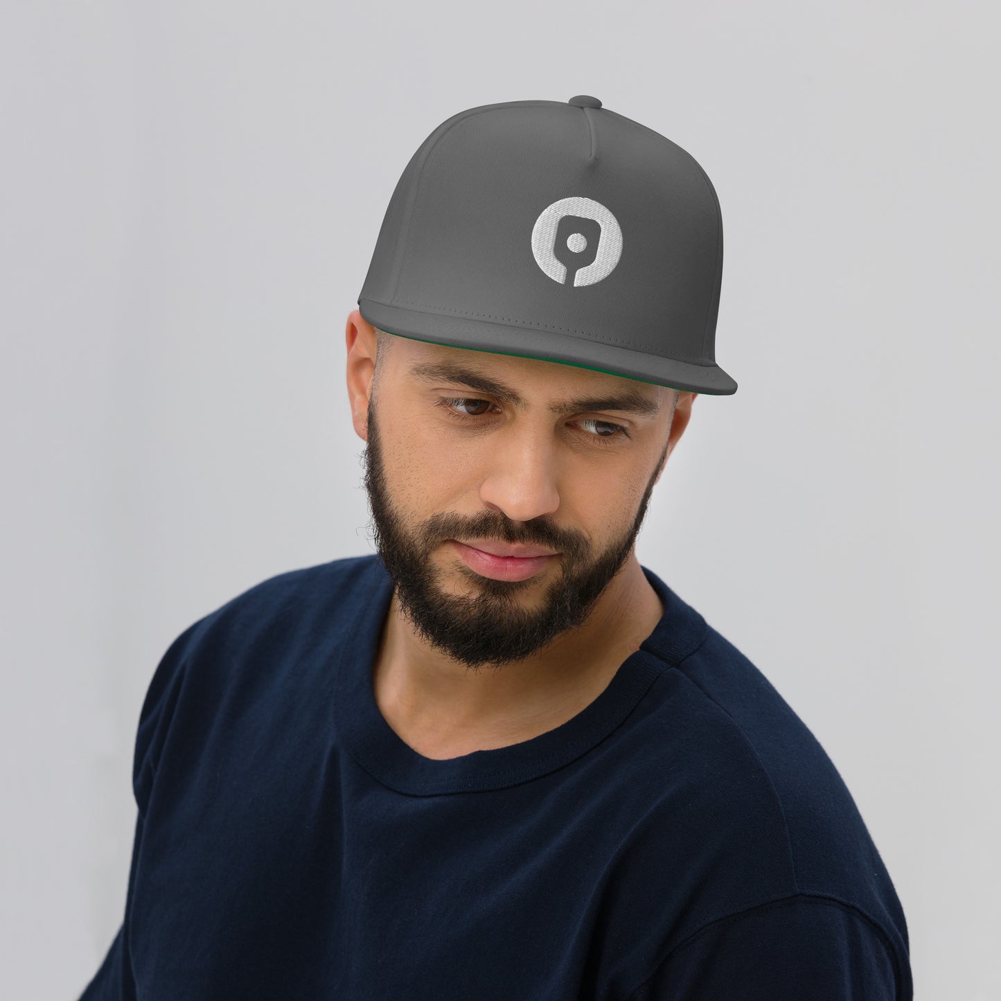 A bearded man wearing a Pickleballist Signature Logo Flat Brim Pickleball Hat and a dark shirt looks slightly to the side against a plain background.