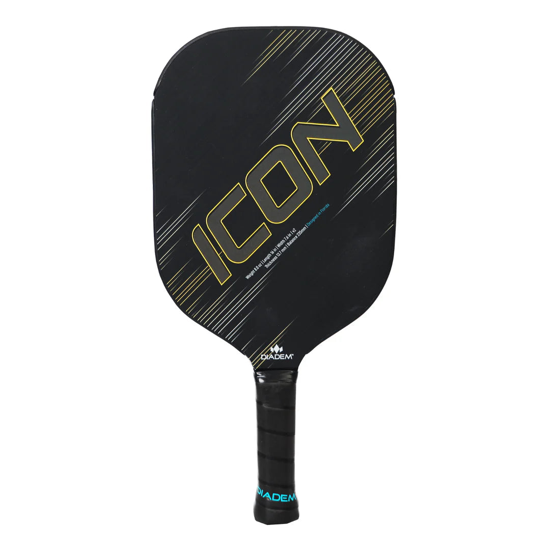 The Diadem Icon V2 Standard Pickleball Paddle by Diadem features a black face with diagonal gold and gray lines, a black handle wrapped with grip tape, and the word "ICON" boldly displayed on the front.