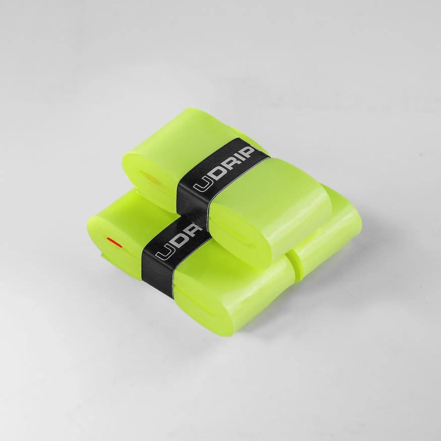 Two translucent bright green strips, each rolled and secured with black bands labeled "UDRIPPIN," are placed on a light gray surface. These are UDRIPPIN Pro Tour Extra Tacky Overgrips.