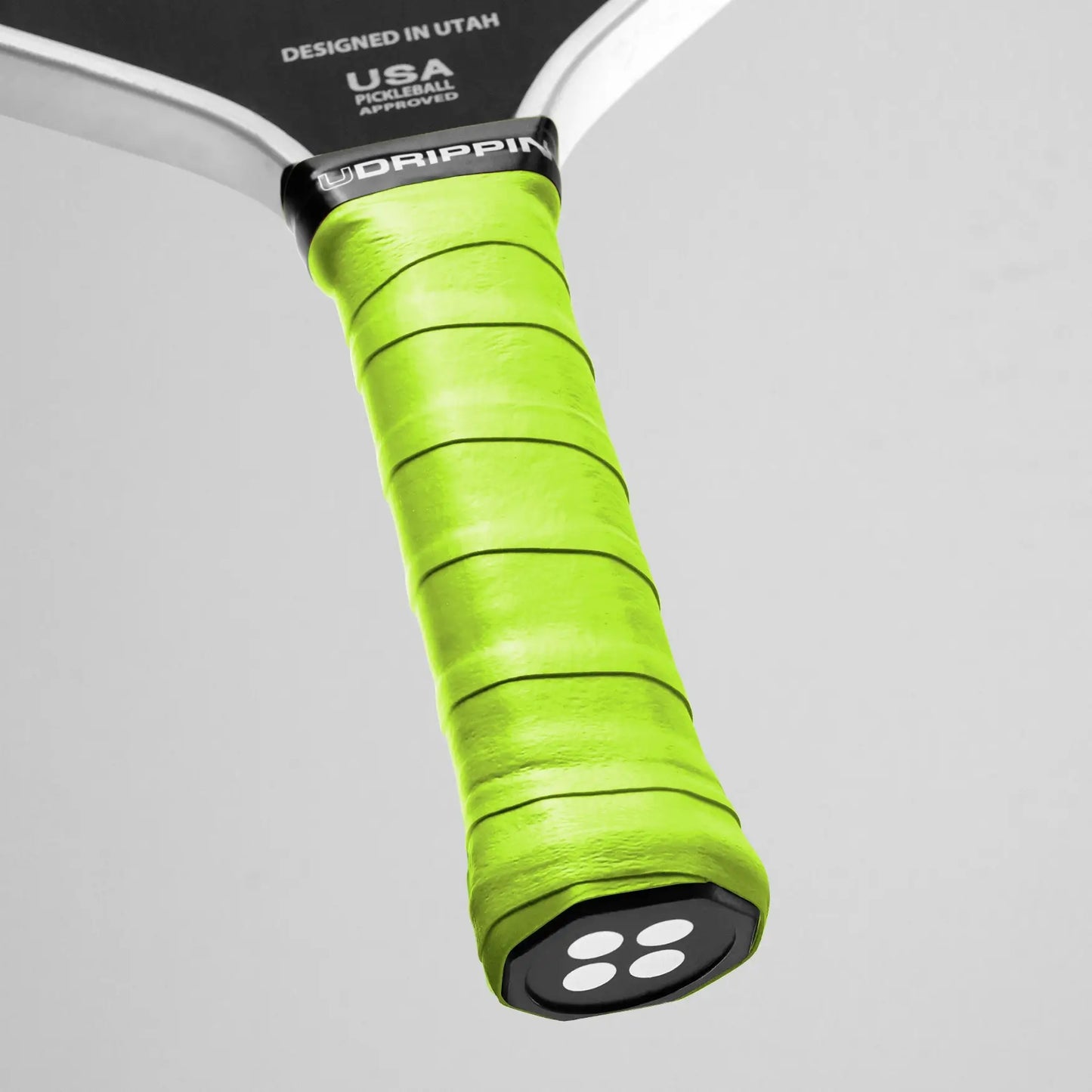Close-up of a pickleball paddle handle wrapped with UDRIPPIN Pro Tour Extra Tacky Overgrips in bright green, boasting the word "UDRIPPIN" near the top.