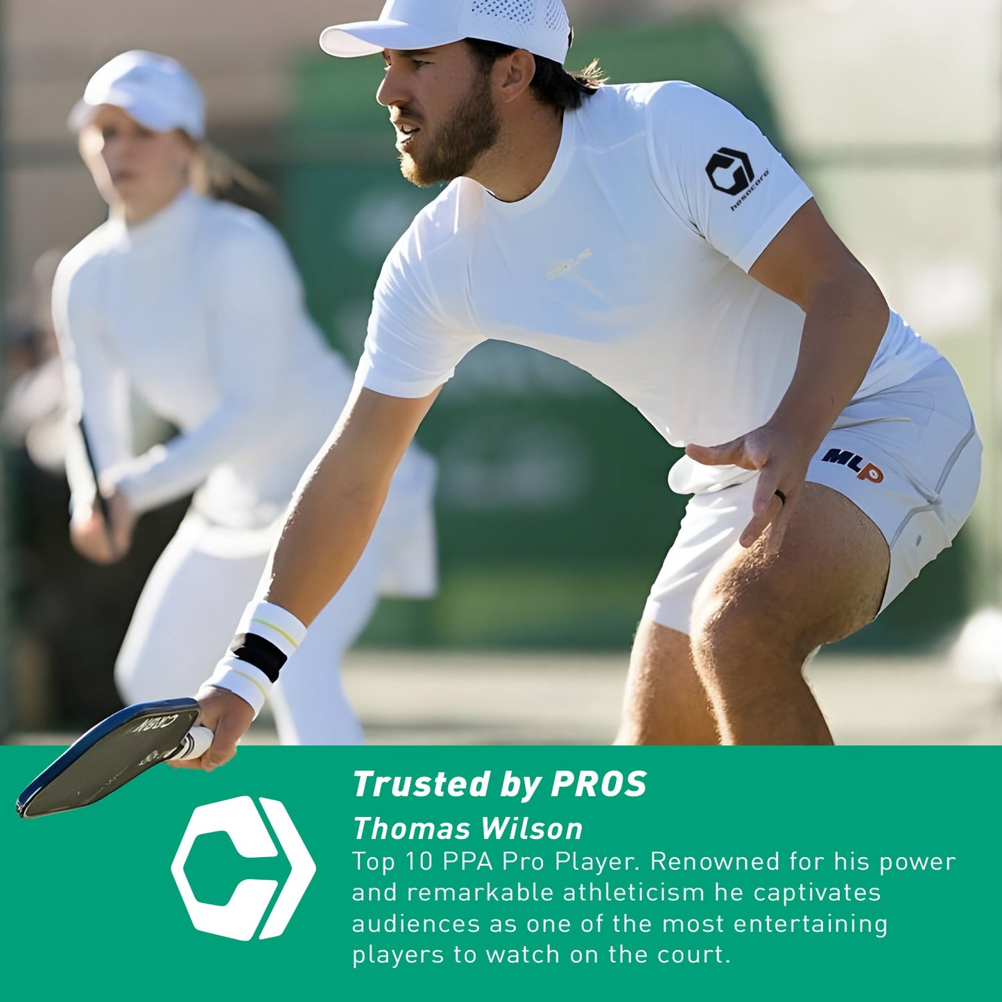 A man in white sportswear plays pickleball, holding a paddle with Hesacore Gel (Light Blue) Pickleball Grip, while another person stands in the background. A green overlay mentions Thomas Wilson as a pro player.