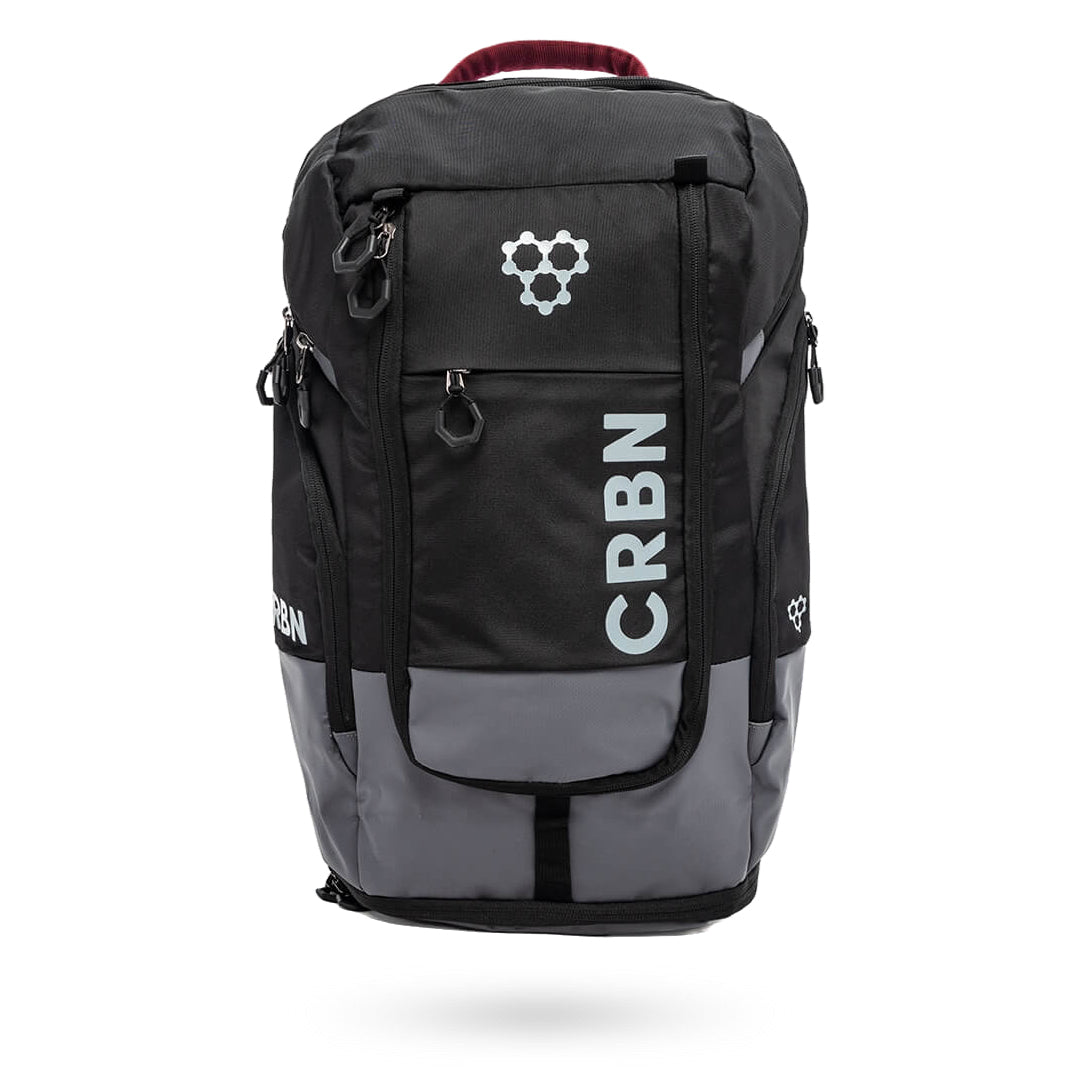 A CRBN Pro Team Backpack Pickleball Bag with the brand name "CRBN" printed in white on the front and hexagonal logos on the top and side. It has multiple zippers and a red handle.