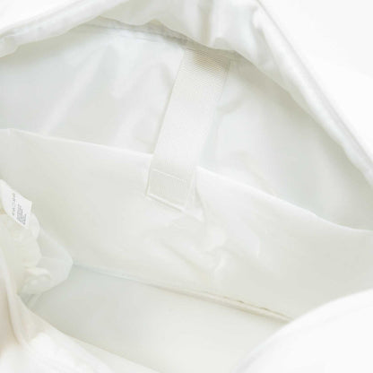 The image shows the inside of the JOOLA Overnighter Puff Bag, a white pickleball bag by JOOLA, featuring a fabric loop and a small inner pocket set against a smooth, light-colored lining and durable construction.