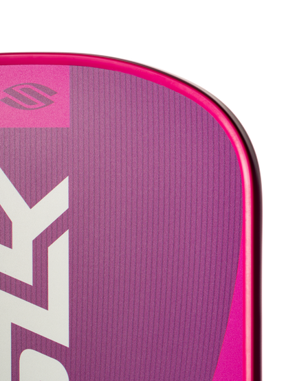 Close-up of the top corner of a Selkirk SLK Valkyrie Widebody 16mm Pickleball Paddle in pink and purple, featuring bold white branding and logo, set against a plain white background.