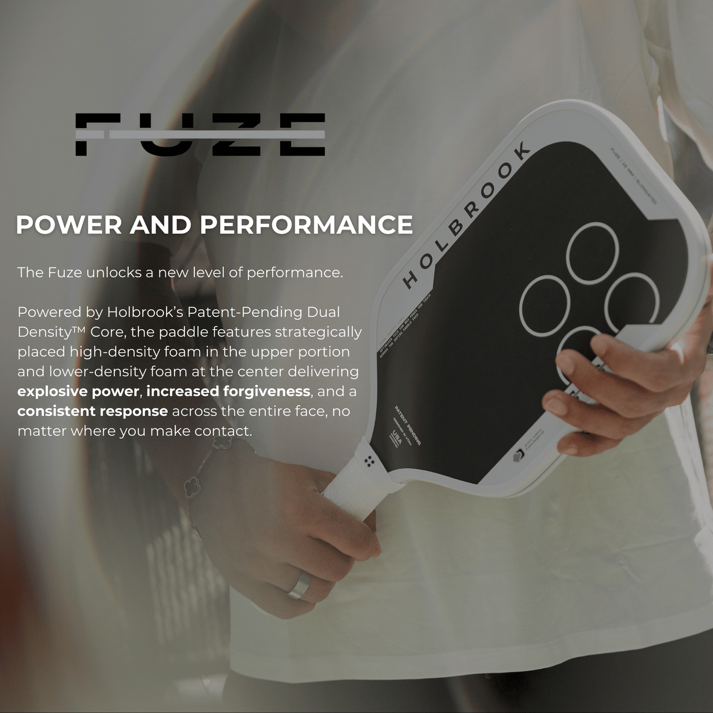 A person holds a Holbrook Fuze Elongated 16mm Pickleball Paddle, featuring a Dual Density Foam Core, with marketing text about its benefits in the background.