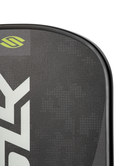 Close-up of the Selkirk SLK Valkyrie Widebody 16mm Pickleball Paddle, showing its black textured surface, partial white Selkirk logo, and a small green emblem at the top.