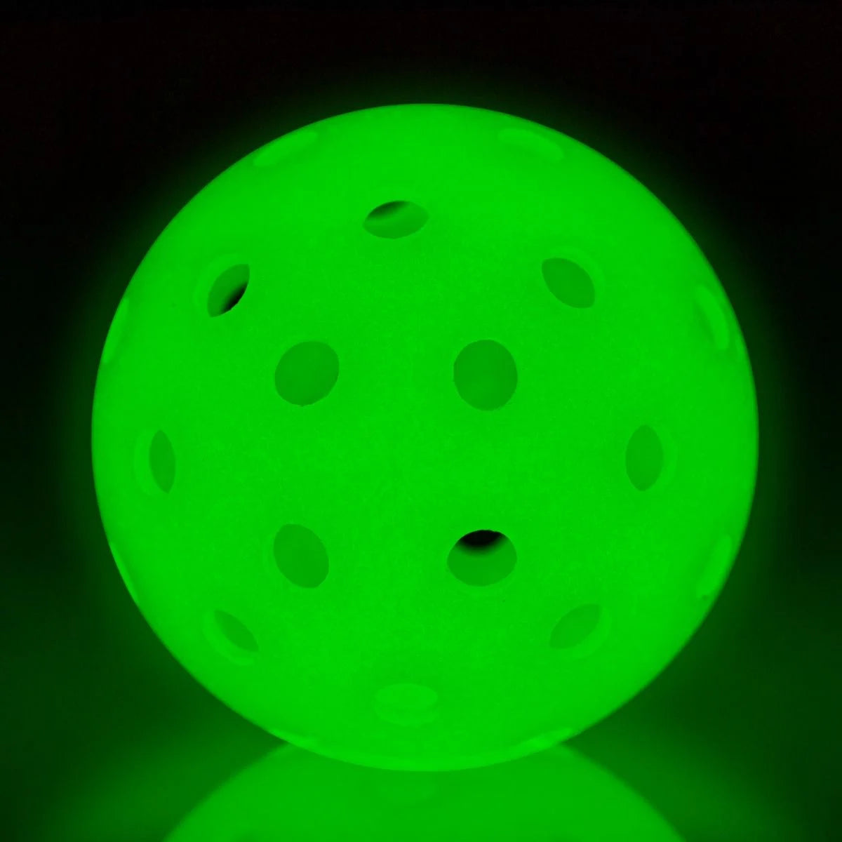 A Franklin X-40 Glow-In-The-Dark Pickleball Ball with dots on it in the dark used for pickleball game.