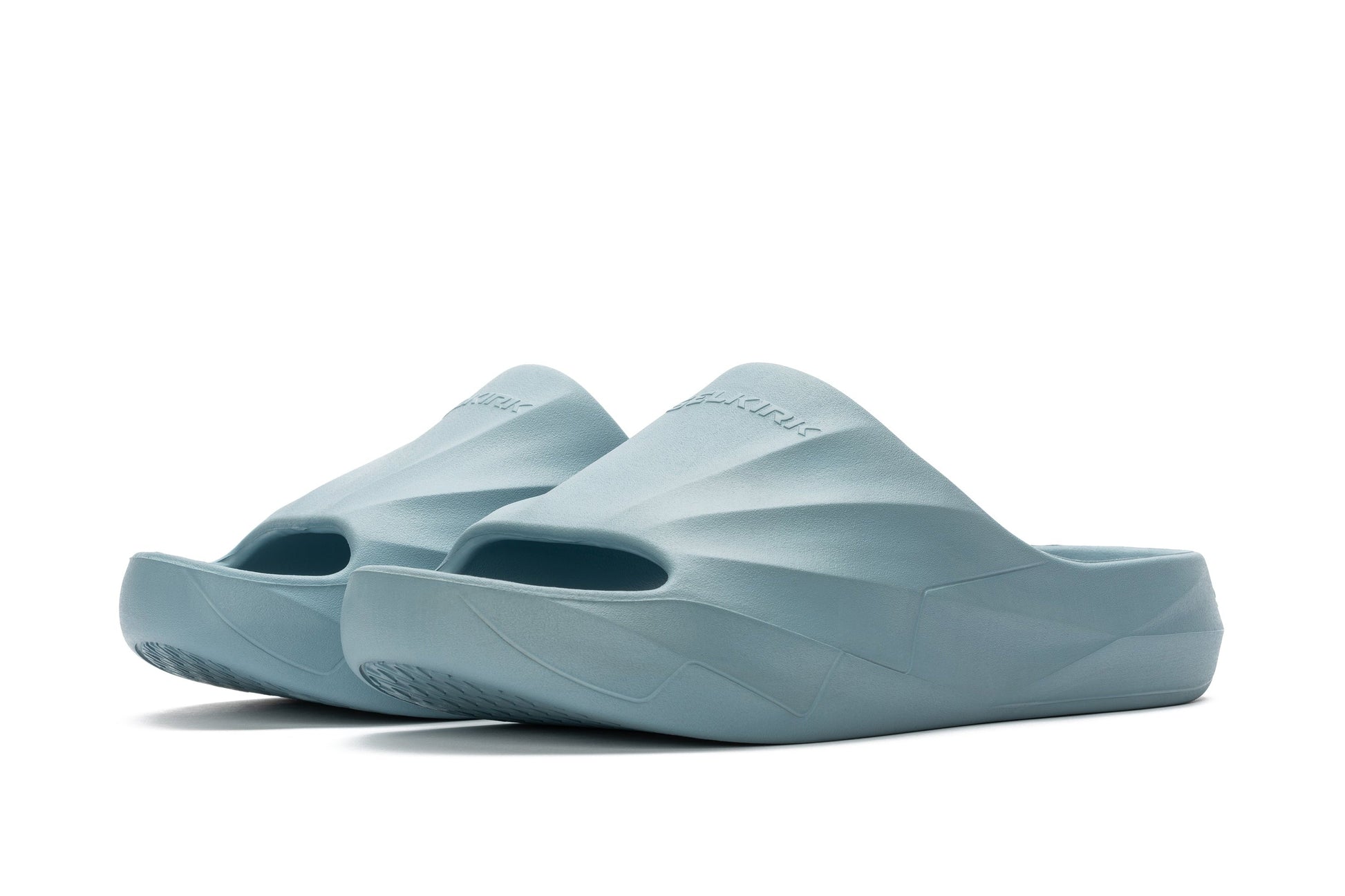 A pair of Selkirk Podium Slide Sandal Pickleball Shoes in light blue, featuring a closed-toe design and textured soles, displayed against a white background.