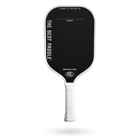 A black and white The Best Paddle Carbon Fiber X Pickleball Paddle on a white background.