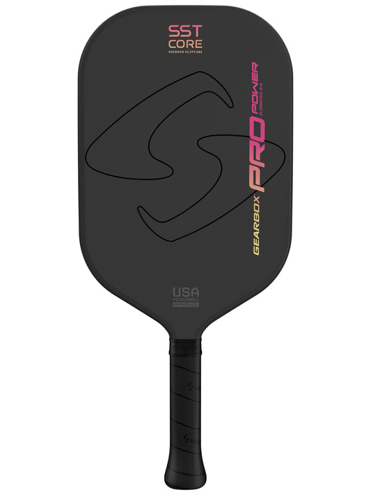 A close-up view of a **Gearbox Pro Power Elongated Pickleball Paddle** with "SST Core," "Pro Power," and "**Gearbox**" written on the face. The paddle, part of the Pro Series, features a textured surface and a sleek black handle made from carbon fiber framework.