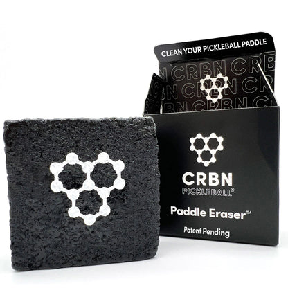 Rectangular black paddle eraser with a honeycomb pattern beside its packaging labeled "CRBN Pickleball Paddle Eraser.