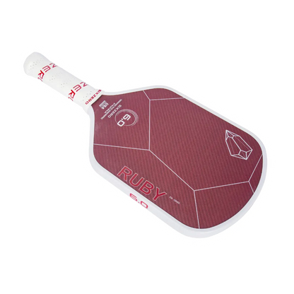 Photo of a red and white pickleball paddle with the brand name "Six Zero" printed on it. The Six Zero Ruby Kevlar (16mm) Pickleball Paddle features a geometric design and a logo.