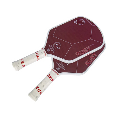 Two red and white pickleball paddles with "Six Zero Ruby Kevlar (16mm) Pickleball Paddle" and geometric designs on the faces, and the brand name "Six Zero" on the handles.