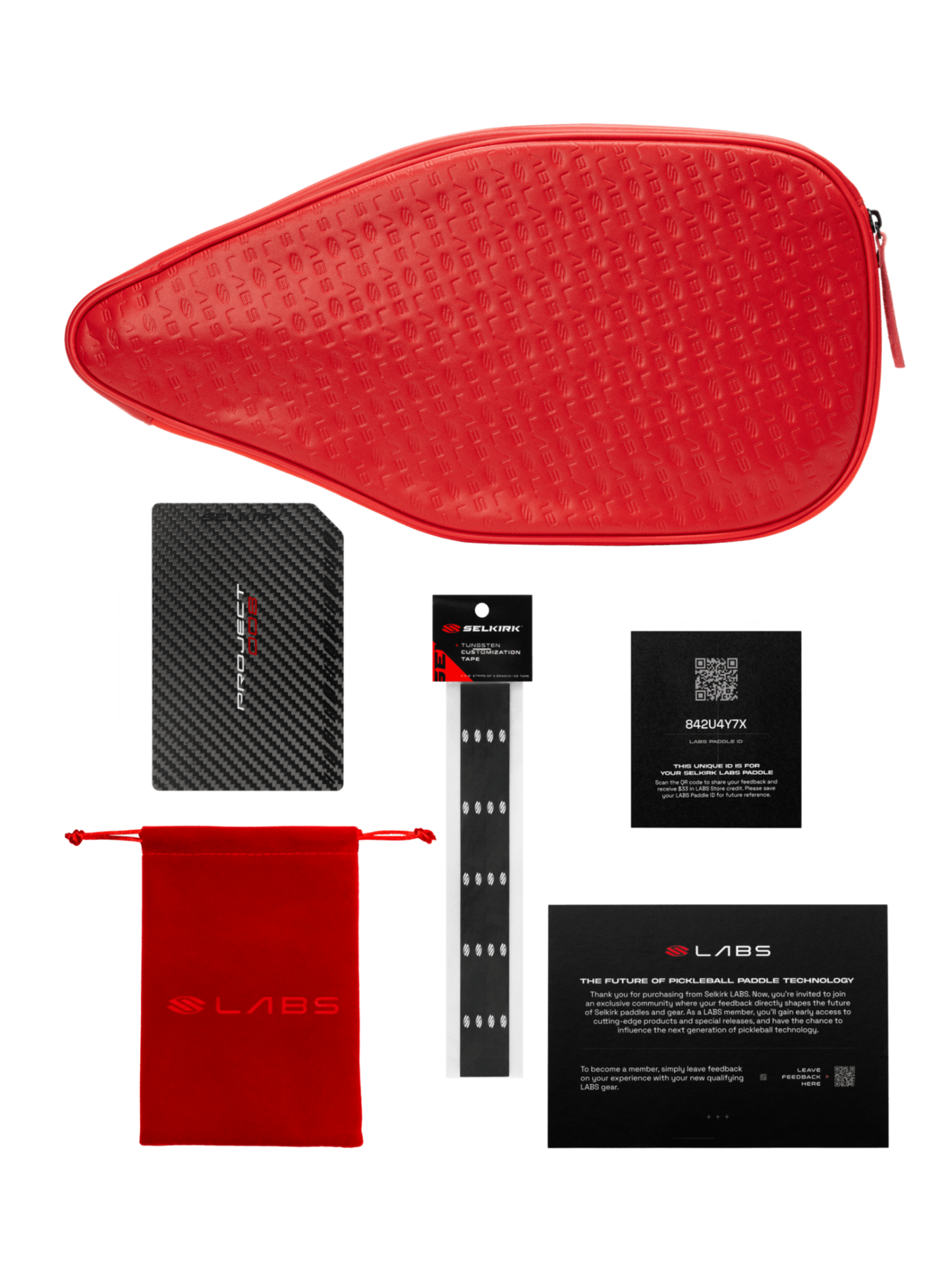 A red zippered pouch, black card, small red pouch, black wristband, black box, and a text card are artfully arranged with the Selkirk Labs Project 008 Invikta Elongated 13mm Pickleball Paddle by Selkirk on a white background.