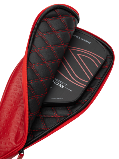 The Selkirk Labs Project 008 Invikta Elongated 13mm Pickleball Paddle, featuring a sleek black design with red accents, is partially visible inside its matching black and red quilted case.