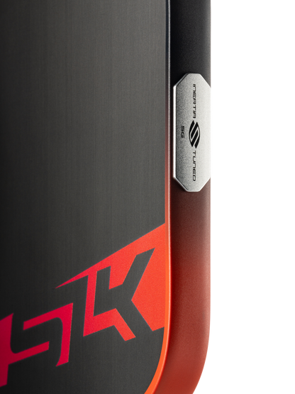 Close-up of a ski features a black and red design with "HK" and a metal plate marked "INERTIA S TURBO ESS," recalling the bold graphics on the Selkirk SLK Dauntless Elongated 16mm Pickleball Paddle by Selkirk.