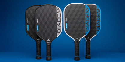Four Diadem Edge BluCore Pro 16mm Pickleball Paddles with black and blue geometric designs stand upright against a blue background, highlighting the sleek style of these paddles from Diadem.