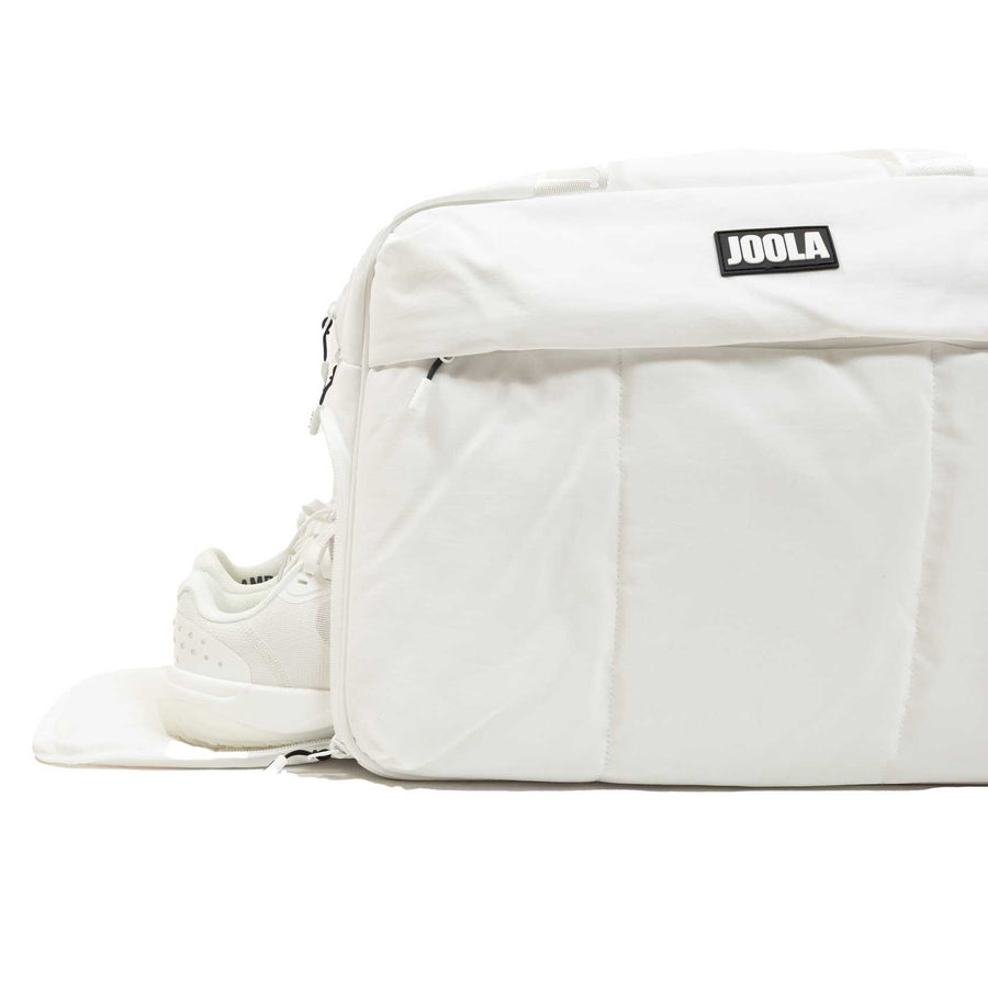 The JOOLA Overnighter Puff Bag, shown in white with a side compartment partially unzipped to reveal a white sneaker, highlights its durable construction for dependable everyday use.
