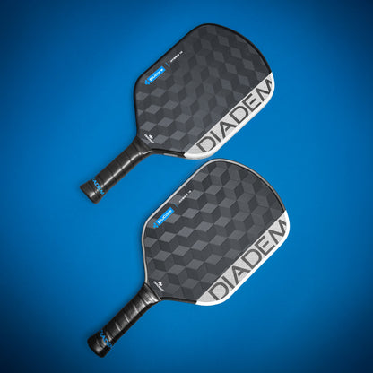 Two Diadem Edge BluCore Hybrid 14mm Pickleball Paddles, featuring black textured surfaces with bold white branding, are displayed side by side on a blue background.
