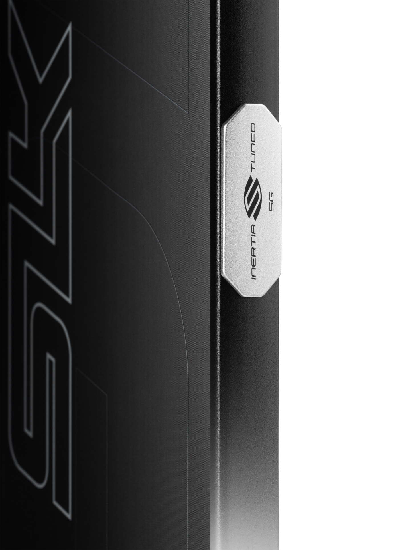 Close-up of a metallic badge with a stylized "S" logo, labeled "INARTA TUNED 5G," attached to a Selkirk SLK GEO Widebody 14mm Pickleball Paddle by Selkirk, resting on a black surface.