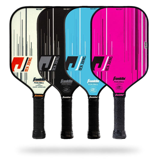 Four Franklin Ben Johns Signature Pickleball Paddles are shown upright. They come in different colors: white, black, blue, and pink, each with a black handle and a modern design with stripes. These USAPA certified paddles feature MaxGrit technology for increased control and have a durable polypropylene core.