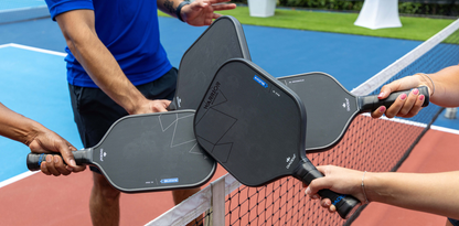 Four players join their Diadem Warrior BluCore Pro Elongated 16mm Pickleball Paddles over the net on an outdoor court, perfectly capturing team spirit and showcasing the quality of Diadem’s top paddle.