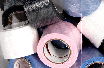 Close-up view of assorted colored rolls of TOURNA TAC® Overgrip Grip Tape - Single Overgrip by Tourna, including black, blue, pink, and white, stacked randomly in a pile.