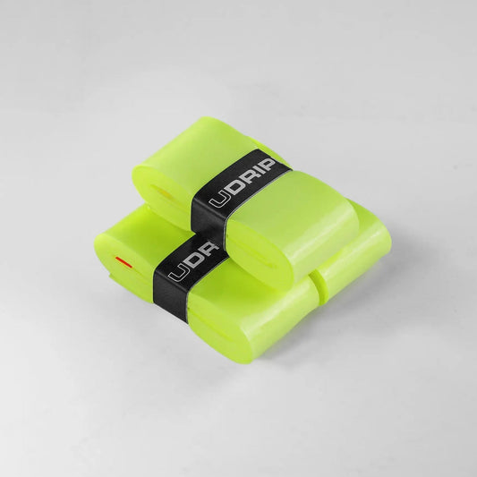 Two translucent bright green strips, each rolled and secured with black bands labeled "UDRIPPIN," are placed on a light gray surface. These are UDRIPPIN Pro Tour Extra Tacky Overgrips.